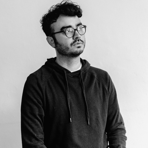 Black and white image of Daniel wearing glasses and looking up at an angle
