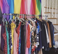 A clothing rack sits in front of a wall of pride flags at the first QT Closet pop-up