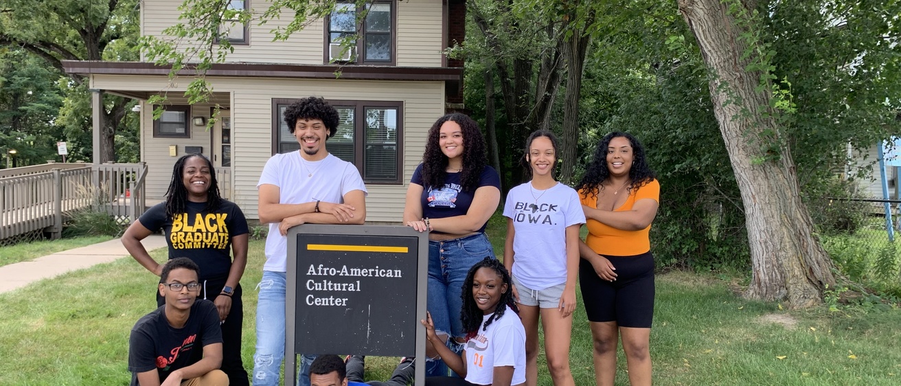 A group photo of the Afro House student staff standing in front of the Afro House sign