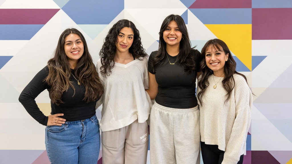 Four Latino Native American Cultural Center staff members smiling into the camera, posing in front of a geometrical background 