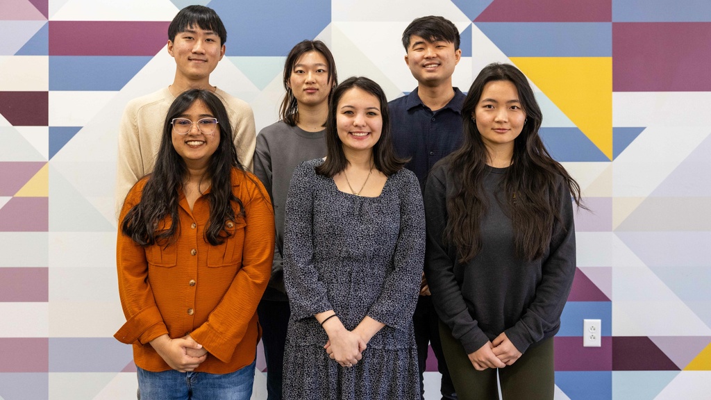 Six Asian Pacific American Cultural Center staff smiling at the camera, posing in front of a geometric background